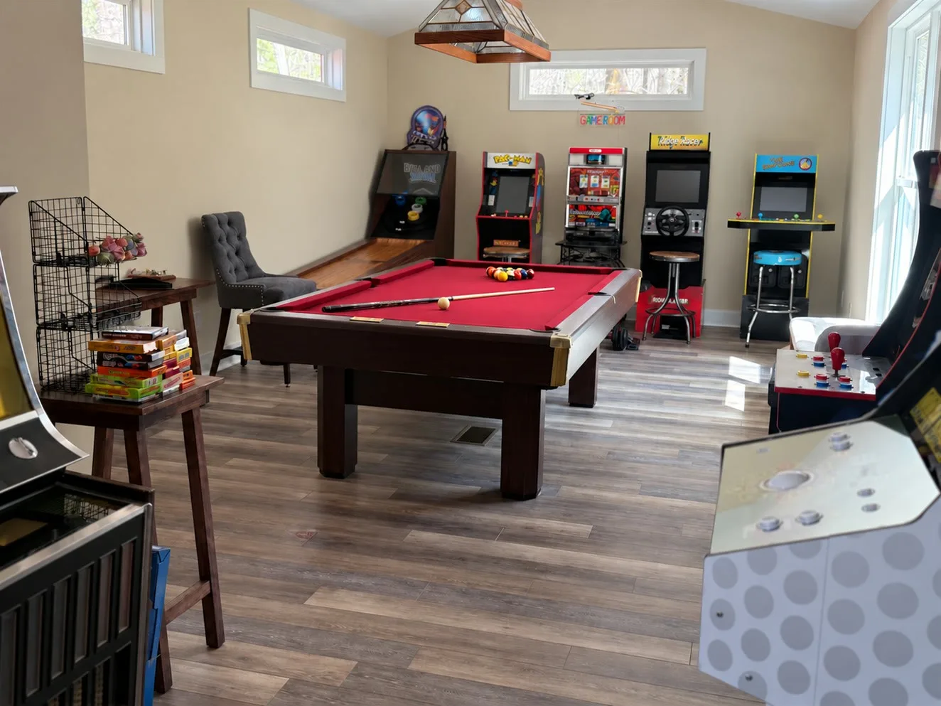 A clean game room with a pool table and arcade cabinets