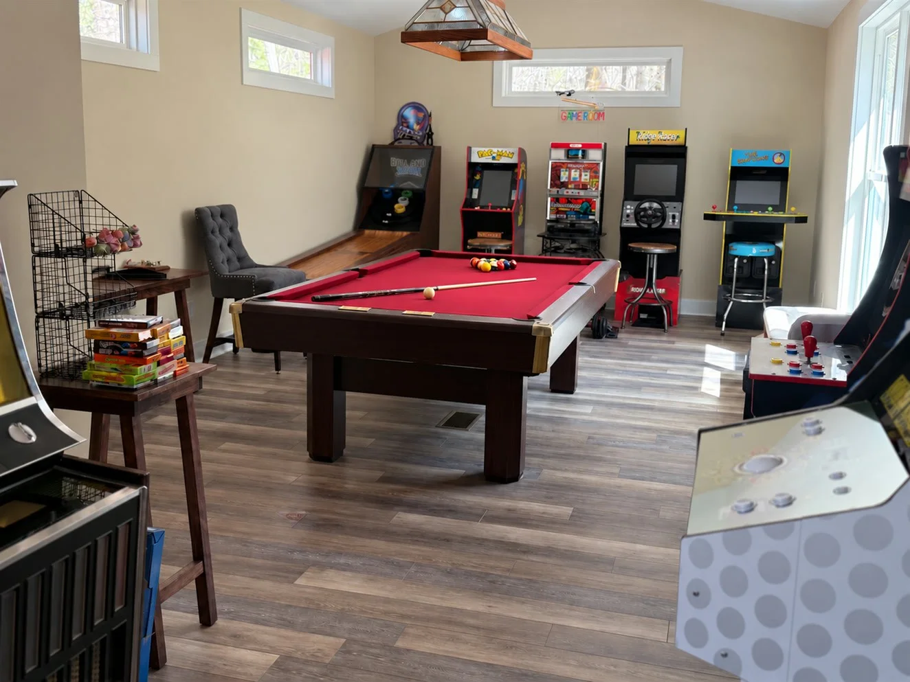 A clean game room with a pool table and arcade cabinets
