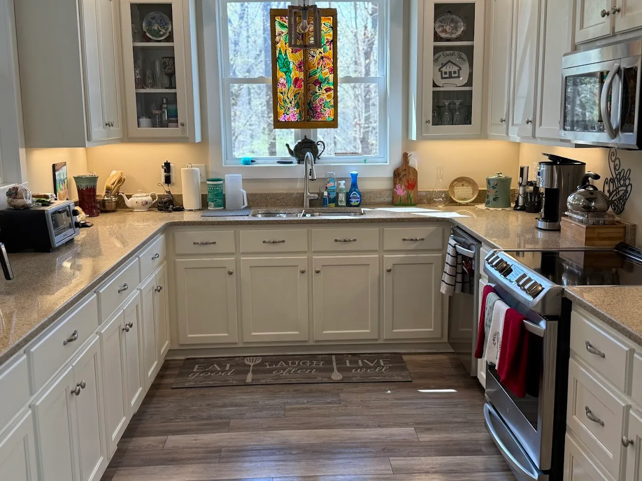 A clean kitchen with white cabinets and a stained-glass panel in the window