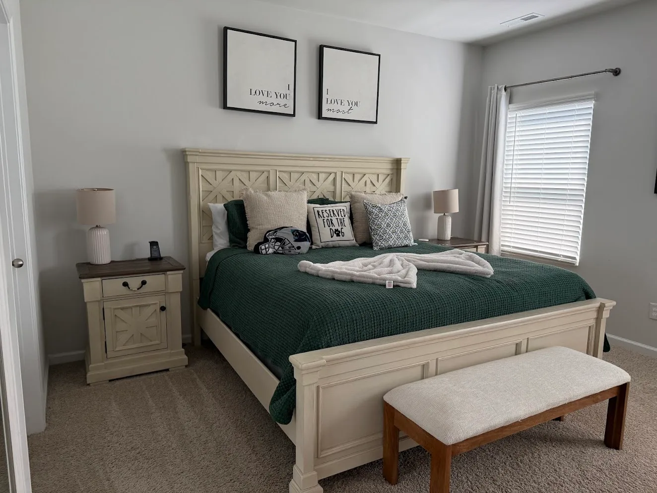 A tidy bedroom with a white bed, green bedding and a bench at the foot of the bed